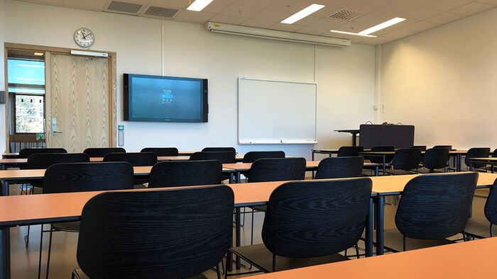 Undervisningsrom med stoler, pulter, skjerm og tavle