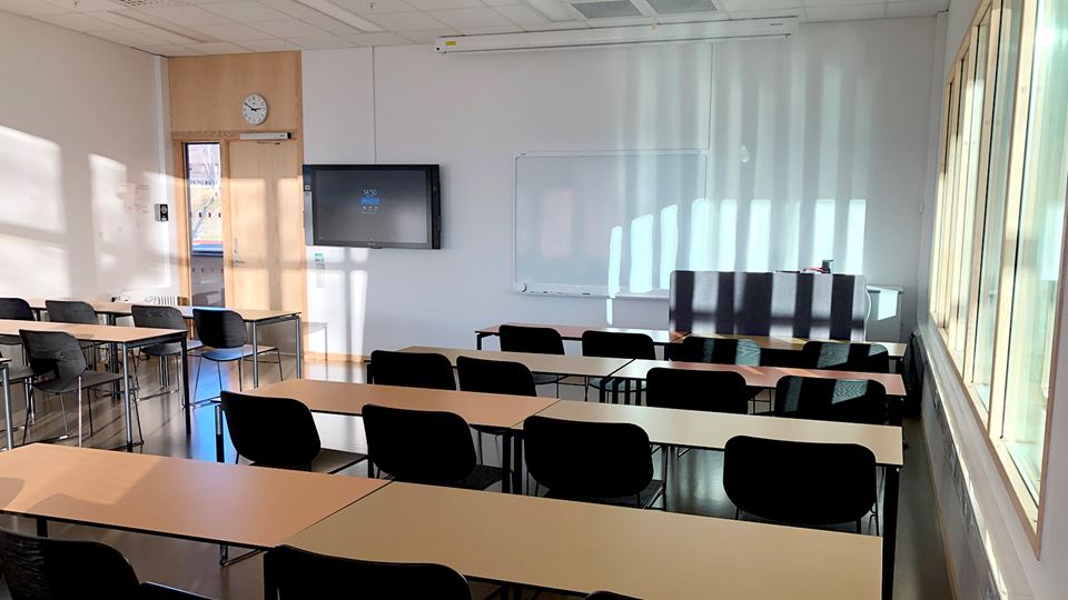 Undervisningsrom med stoler, pulter, skjerm og tavle