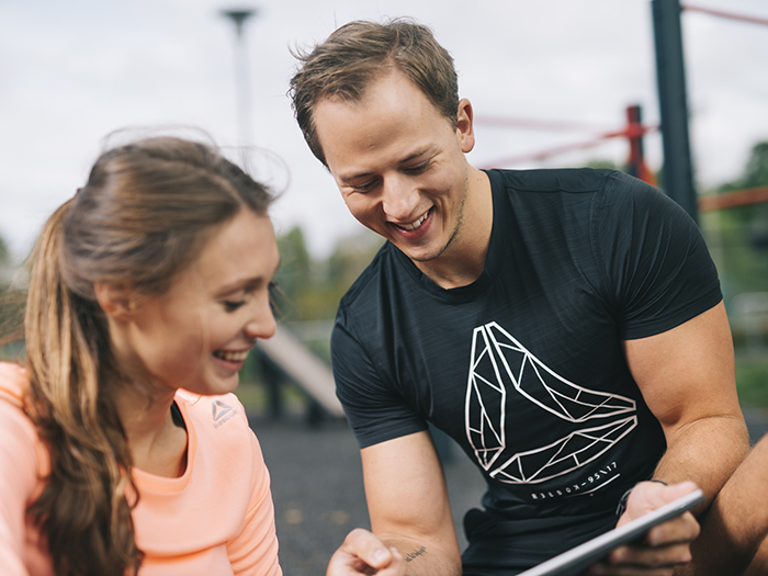 Personal trainer shows results to athlete on a tablet. 