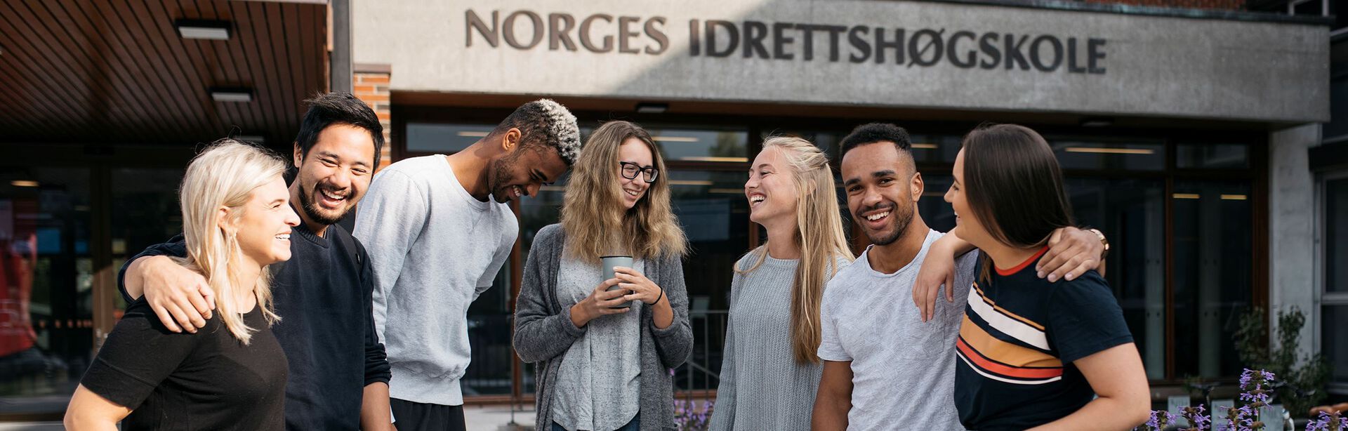Smilende studenter foran inngangen til Norges idrettshøgskole
