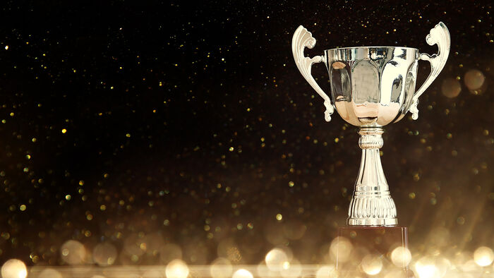 A light trophy against a dark, glittering background