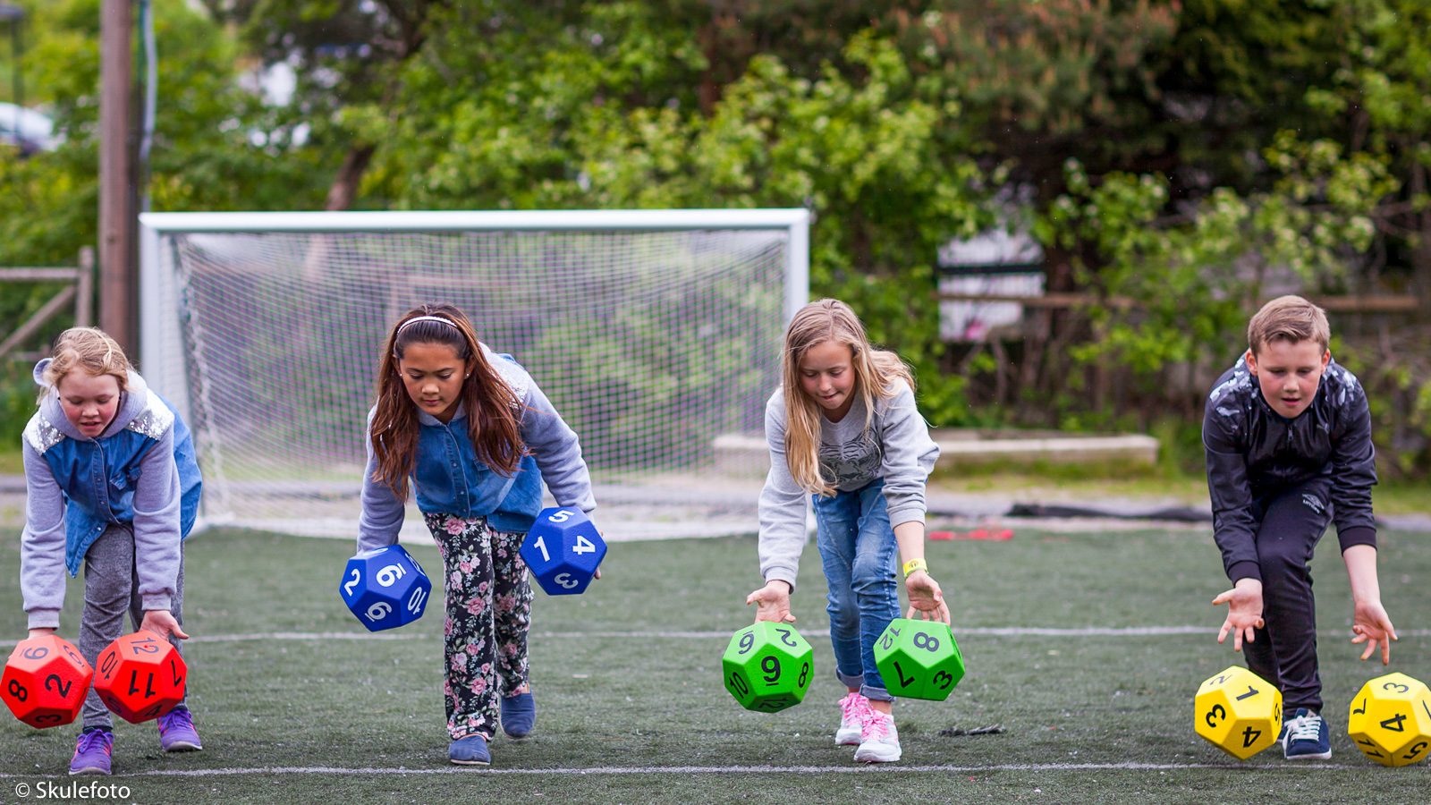 Kids rolling manysided blocks on an outdoor field