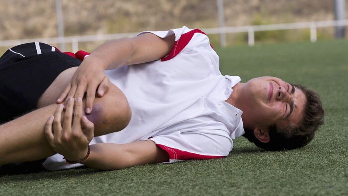 A footballplayer lying on the field with an injured knee