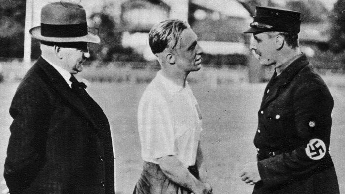 Bilde av fotballspiller Asbjørn Halvorsen i diskusjon med SS-politi
