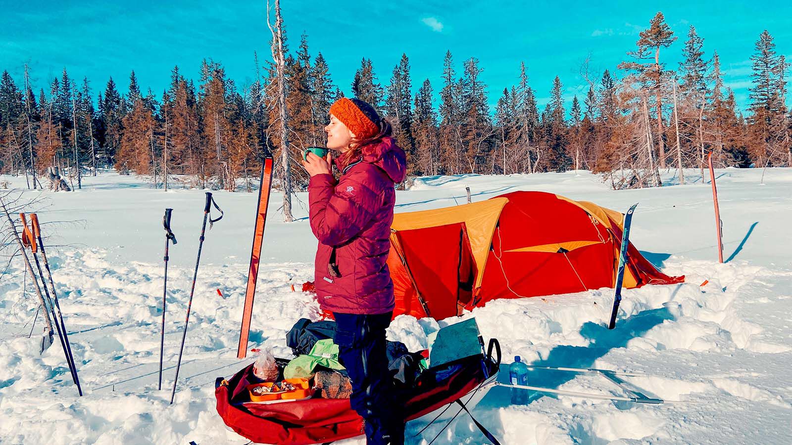 A woman grinning towards the sun on a trip in the snow.