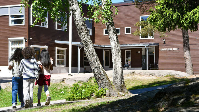 Barn som går i skulegard med tre rundt seg. 