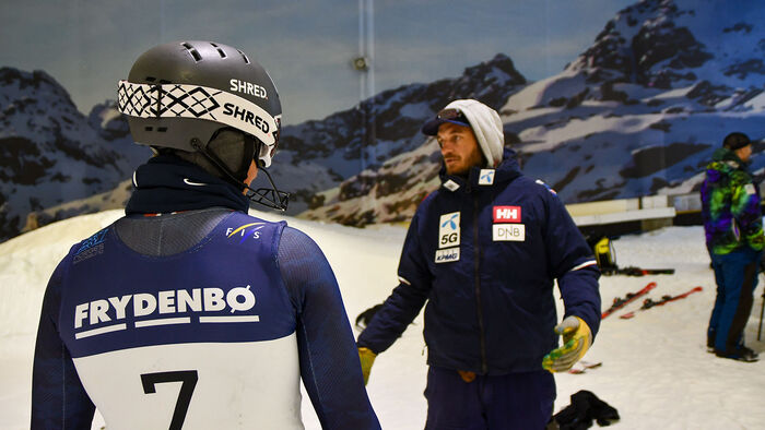 Alpine coach talks to a athlete in a indoor skiing facility