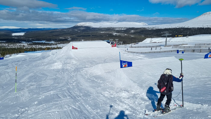 Mann som måler eit skihopp i skicross-løype. 