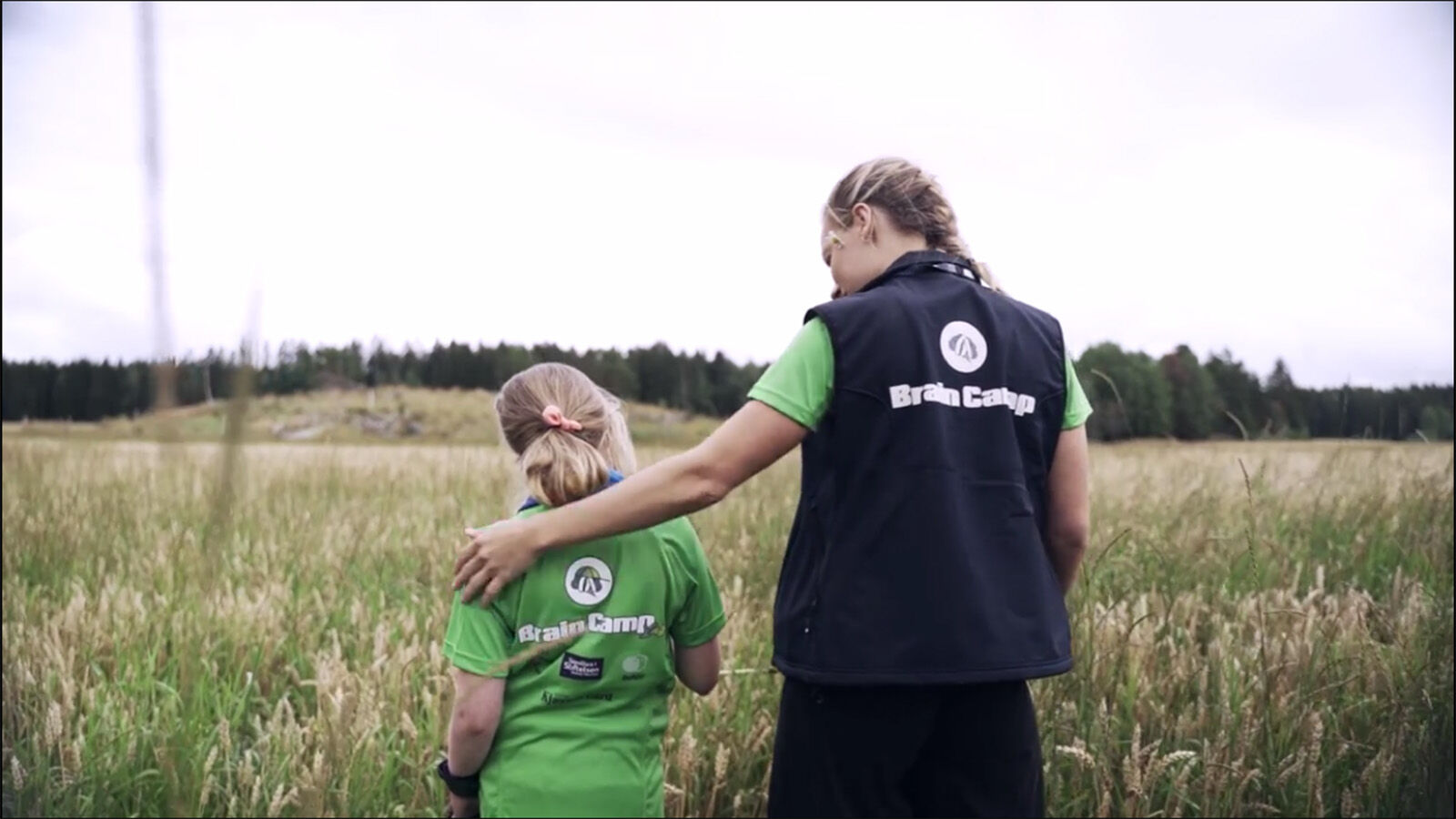 Dame held rundt jente. Det står Brain Camp på ryggen på gensaren