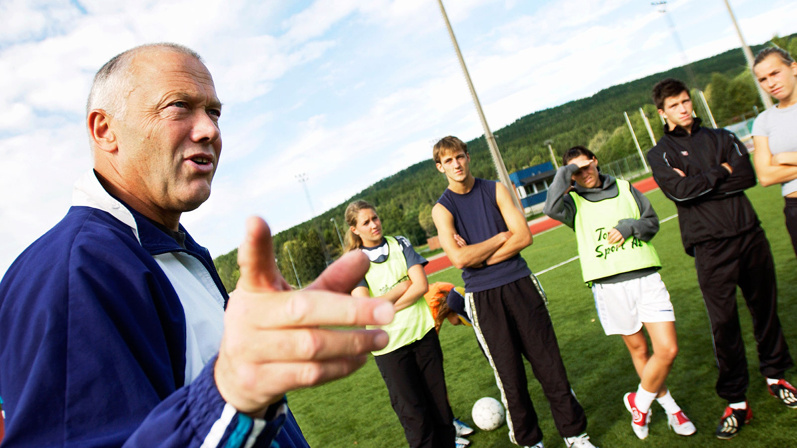 Fotballtrener underviser studenter ute på en fotballbane