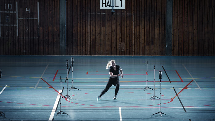 Kvinne som gjør bevegelsesøvelse i en idrettshall