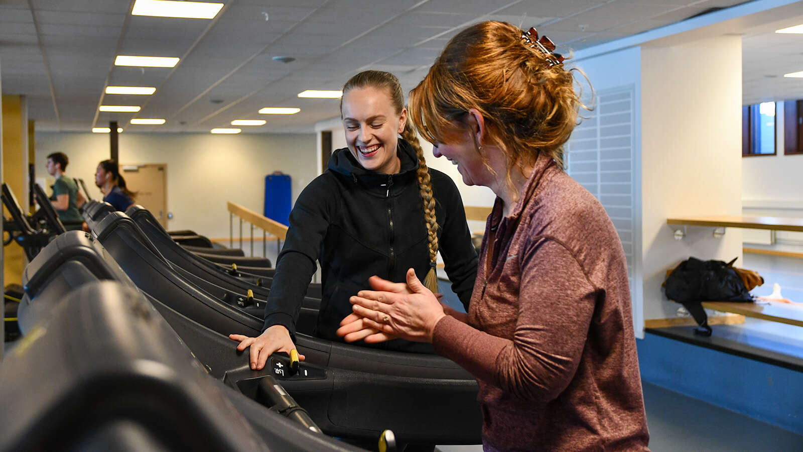 Personleg trenar fylgjer opp på løpetrening på mølle