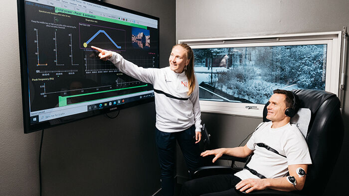 Researcher points to results on screen to a participant who sits in a chair