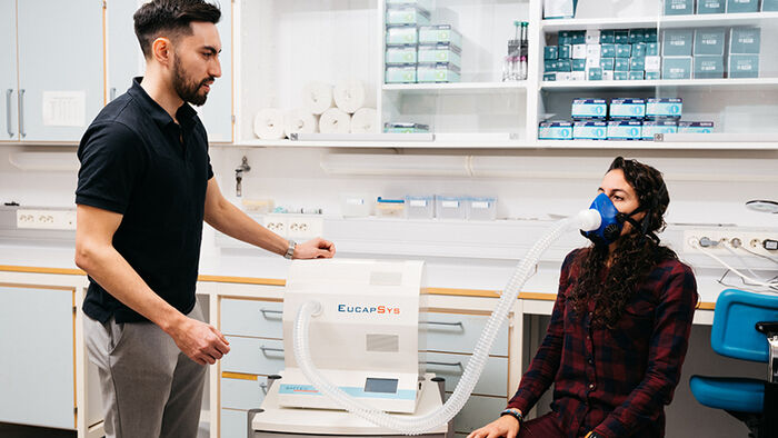 A researcher gives instructions to a particpant wearing a mask that measures airflow