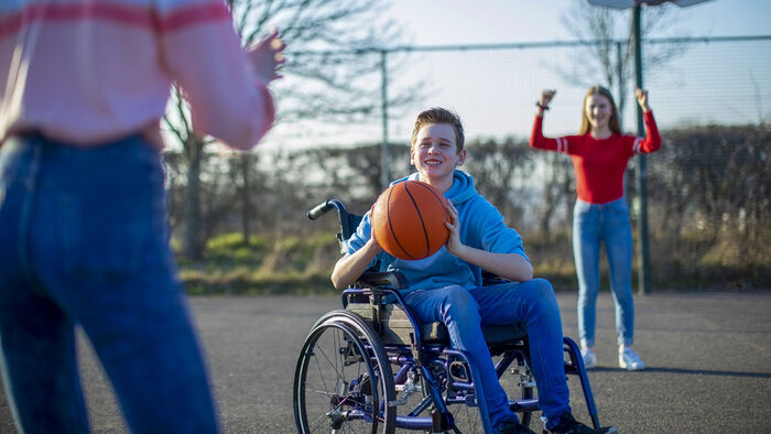 gutt som spiller basketball i rullestol