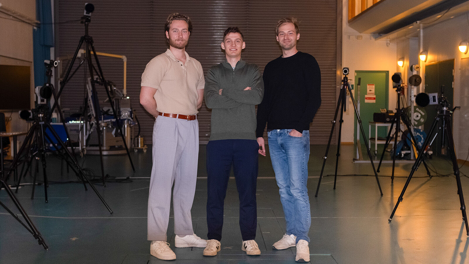Tre menn står i biomekanikklaben med kamera rundt