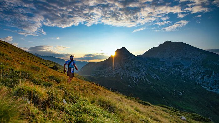 Mann springer på fjellet i solnedgang