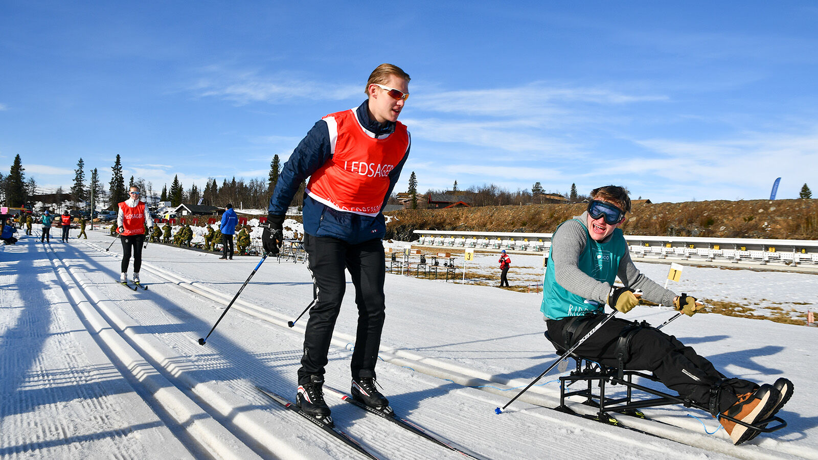 Ledersag fra NIH og en deltager fra Ridderrennet går på ski sammen i sporet.