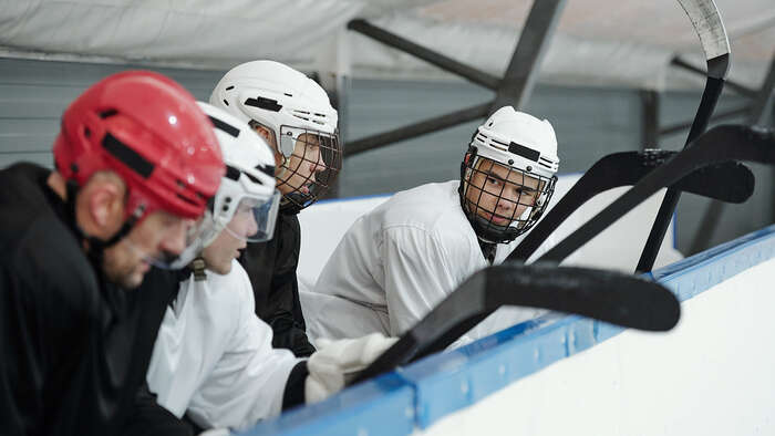 Fire ishockeyspillere sitter utenfor isen. 
