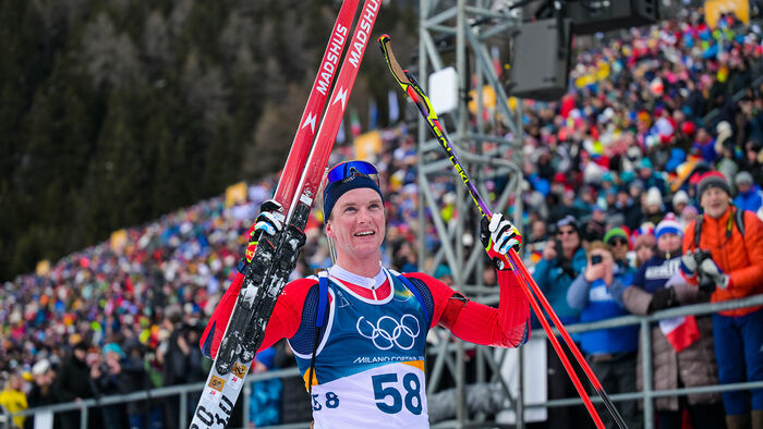 Jublande skiskyttar i mål framfor publikum