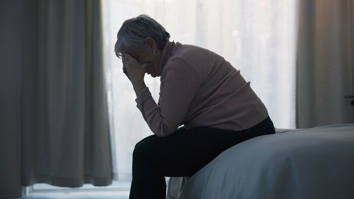 Bilde av deprimert kvinne som sitter på senga.