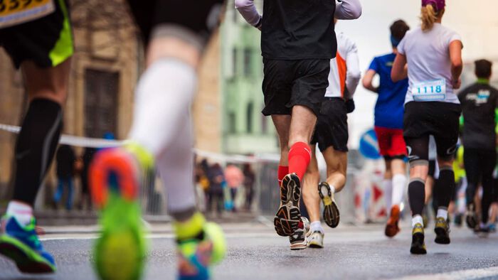 Ein gjeng med løparar som spring maraton i by.