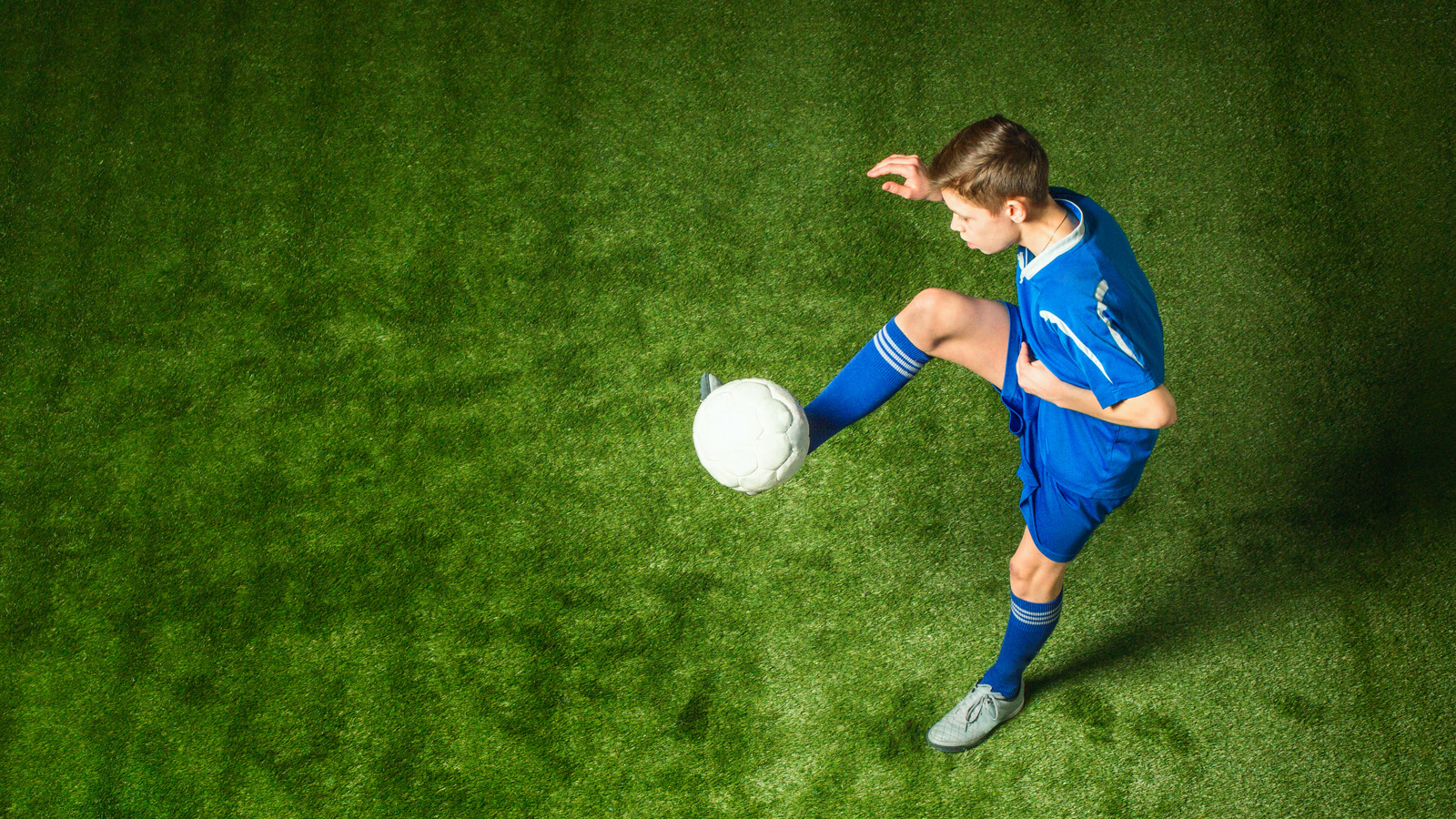 Ung fotballspiller trikser med ball.