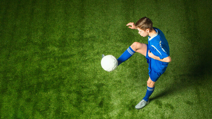 Ung fotballspiller trikser med ball.