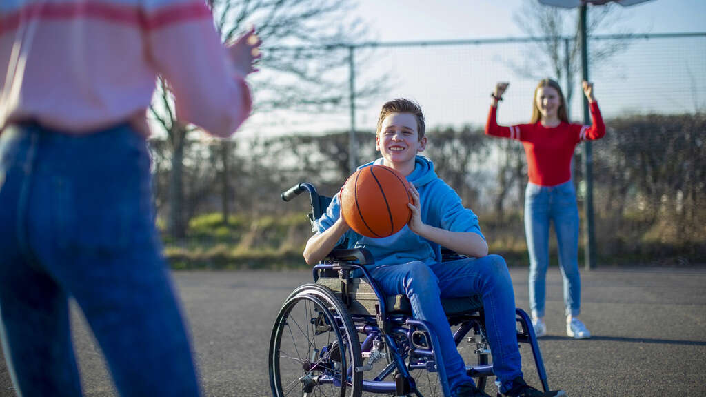 Barn som spiller basket i rullestol