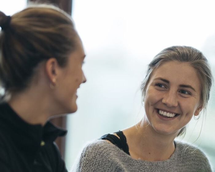 To kvinner smiler til hverandre under en samtale