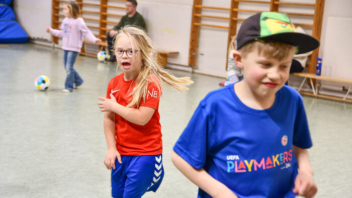 to barn som spiller fotbal i gymsal