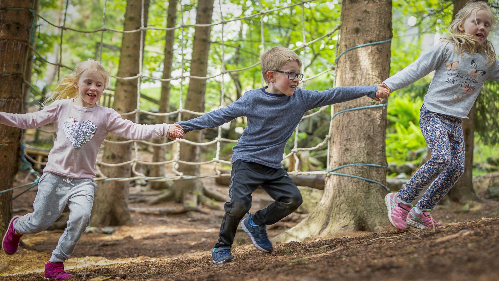 Children in the woods holding hands and running in a circle
