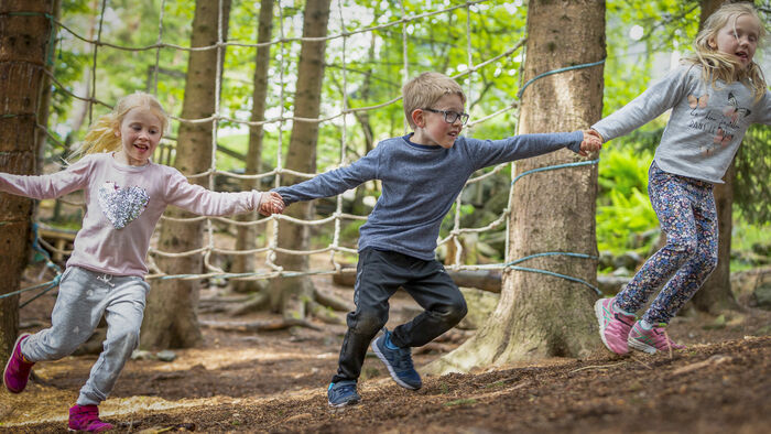 Children in the woods holding hands and running in a circle