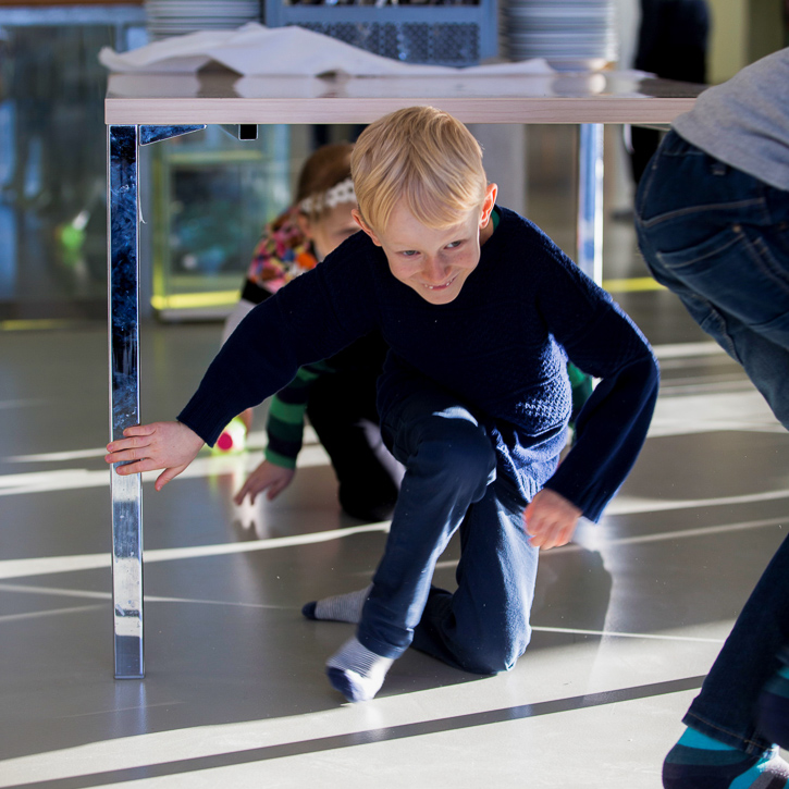 Boy under desk in classroom