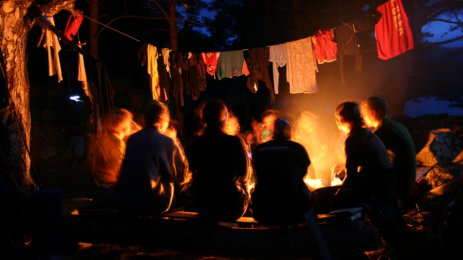 Young people at a camp fire, Clothes are drying on a line above