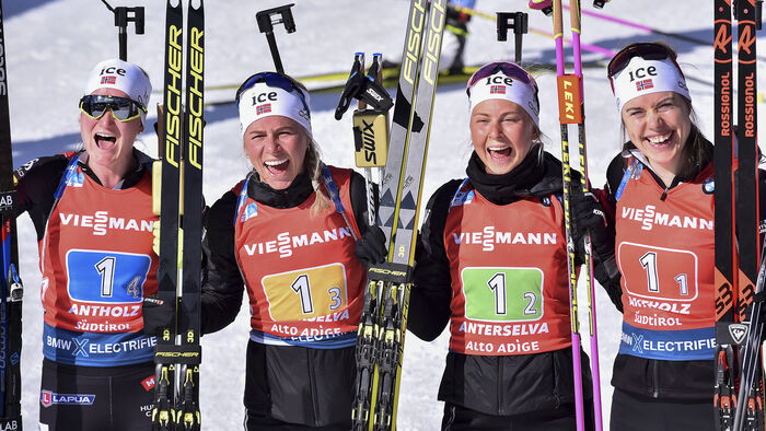 Skiskyttarkvinner jublar etter målgang på VM-stafett. 