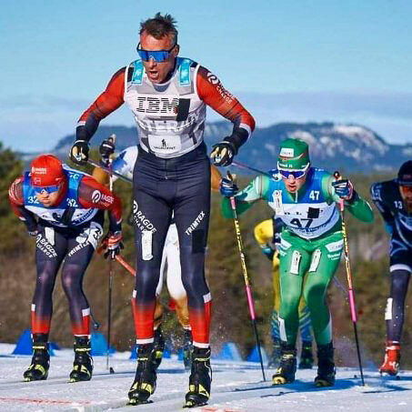 Aukland går skirenn i sol. Her foran i kø av fleire skiløparar