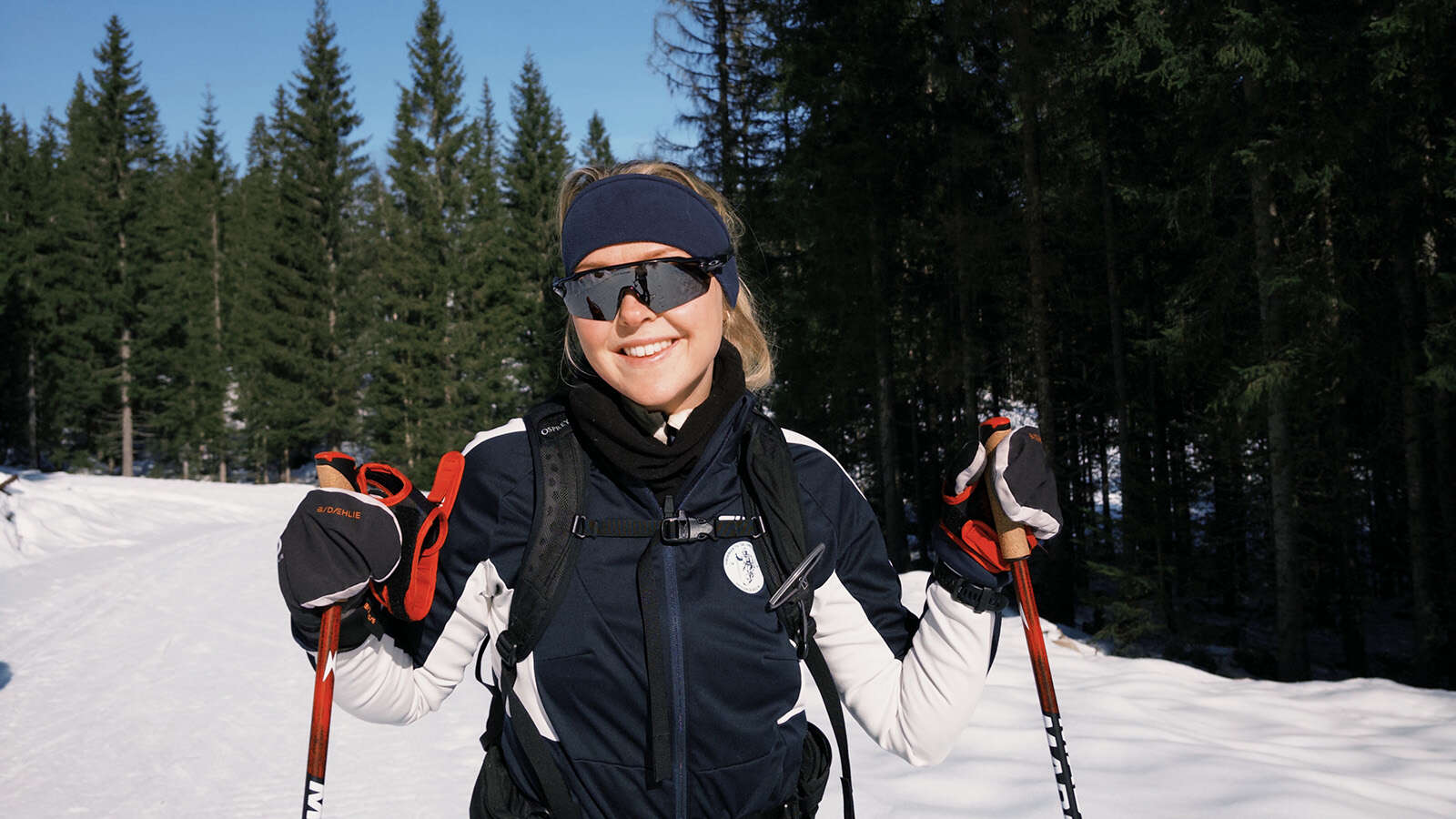 Kvinne smiler på ski i marka