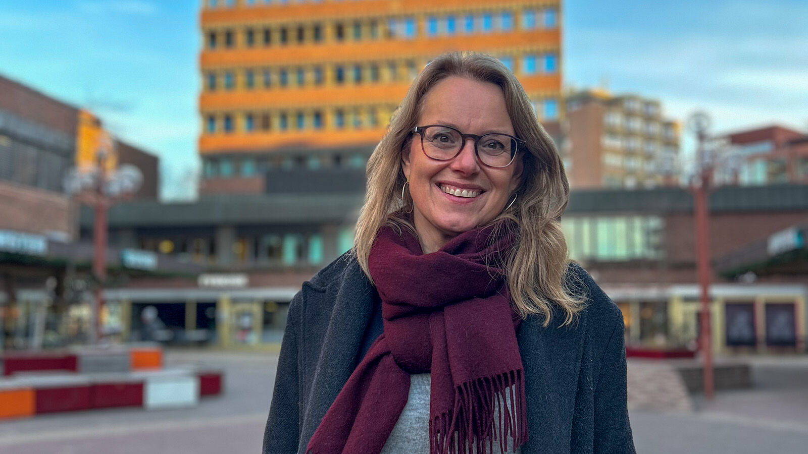 Cathrine Pedersen smiler på Tøyen Torg framfor blokka ho jobbar i.