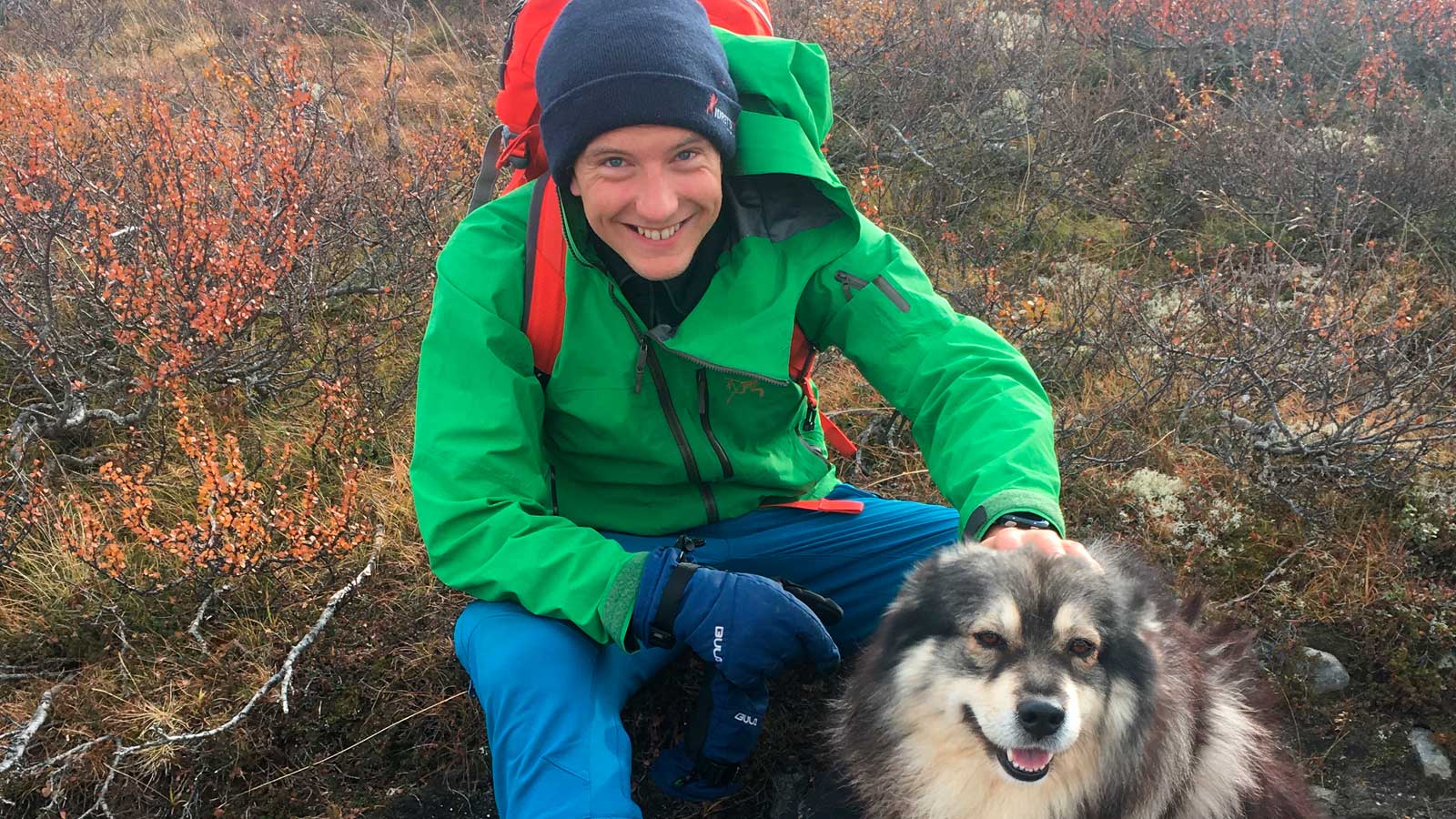 Sigbjørn klapper på hunden sin ut på marka. 
