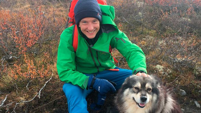 Sigbjørn klapper på hunden sin ut på marka. 