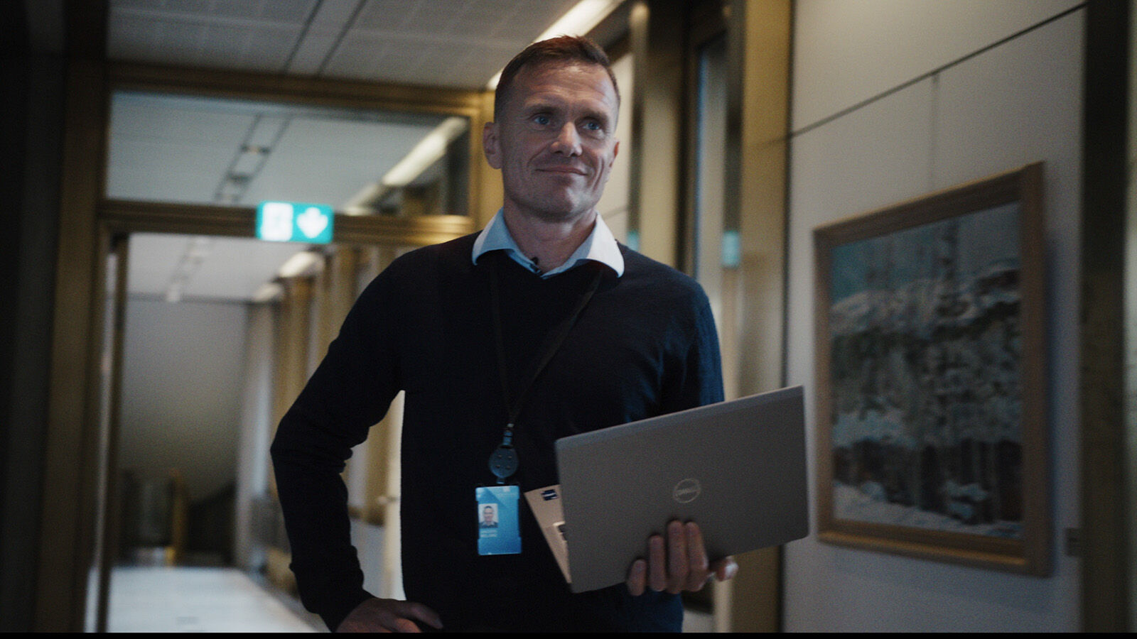 Mann med mac i henda går i ein gang.
