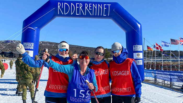 Deltaker sammen med studenter foran målseglet til Ridderennet